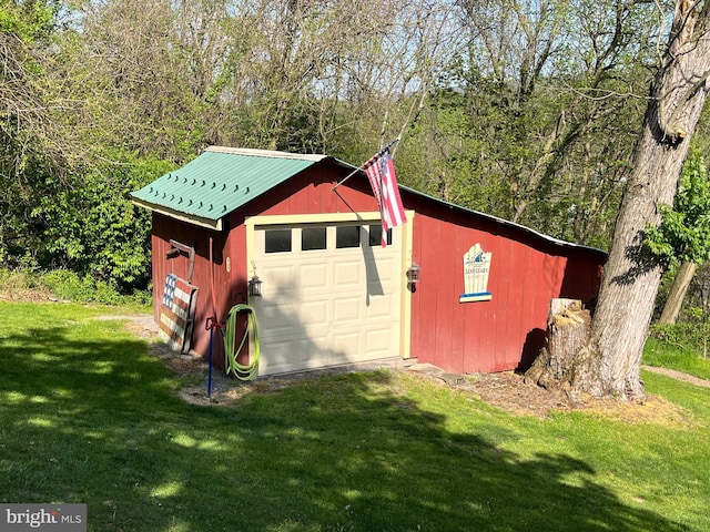 exterior space with a lawn, a garage, and an outdoor structure