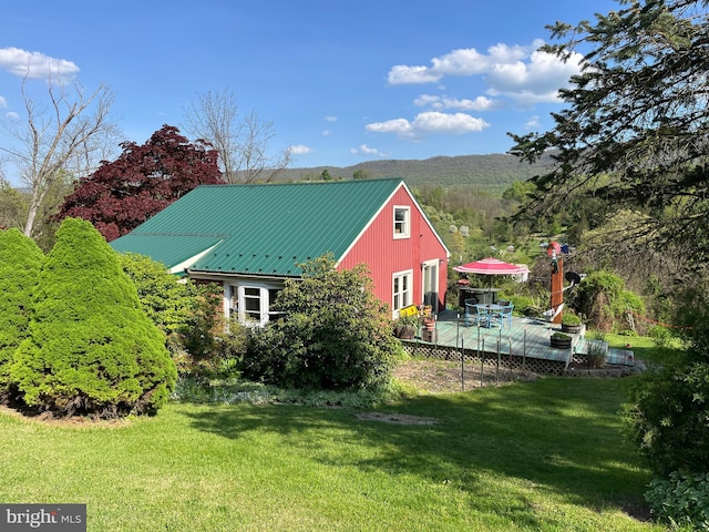 view of side of property featuring a yard and a deck with mountain view