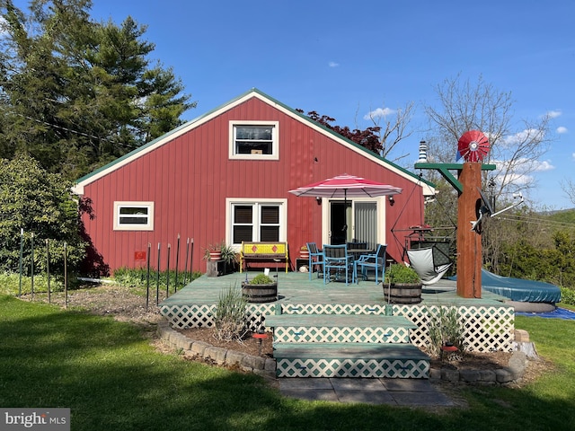 back of property with a deck and a lawn