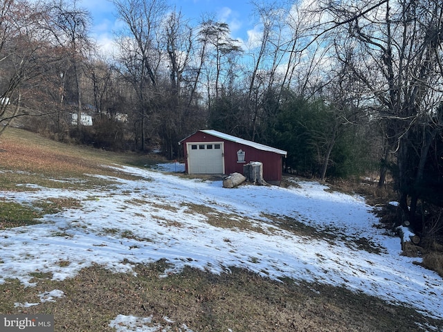 yard layered in snow featuring a garage and an outdoor structure