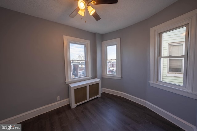 empty room with ceiling fan, dark wood-type flooring, and a textured ceiling