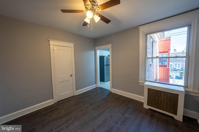 unfurnished room with ceiling fan, radiator heating unit, and dark wood-type flooring