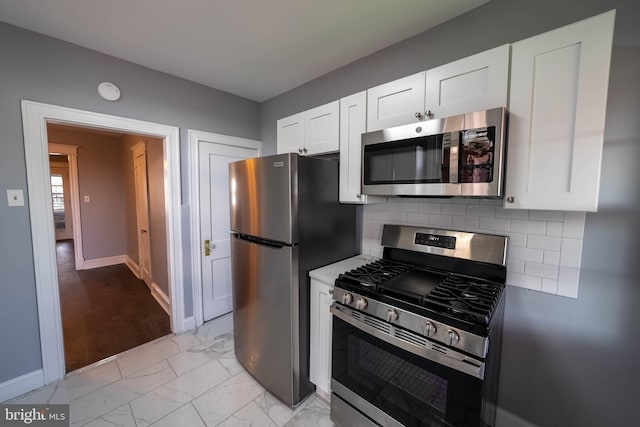 kitchen with backsplash, white cabinets, and appliances with stainless steel finishes