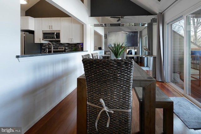 kitchen with white cabinetry, dark hardwood / wood-style flooring, vaulted ceiling, and appliances with stainless steel finishes