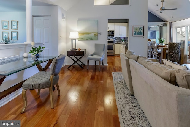 living room with light wood-type flooring, ceiling fan, and vaulted ceiling