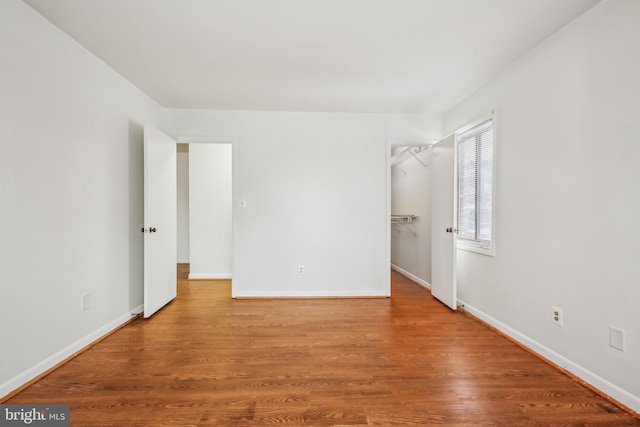 unfurnished bedroom featuring a closet, a walk in closet, and light hardwood / wood-style floors