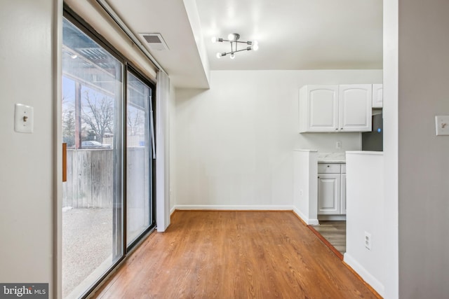 interior space with light wood-type flooring, white cabinetry, and refrigerator