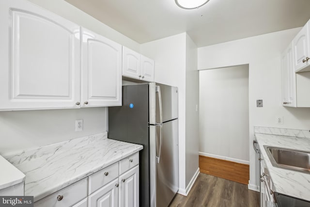 kitchen featuring light stone countertops, white cabinets, dark hardwood / wood-style flooring, sink, and stainless steel fridge