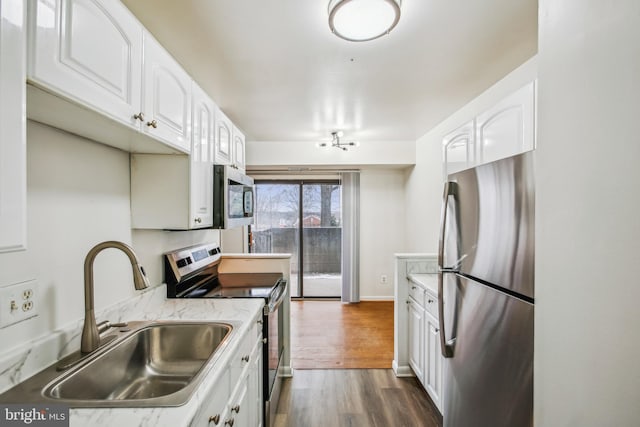 kitchen with dark wood-type flooring, appliances with stainless steel finishes, white cabinets, and sink