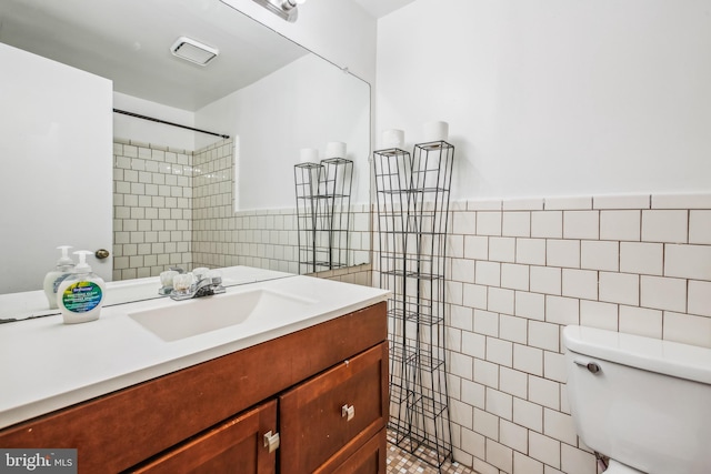 bathroom featuring toilet, tile walls, tiled shower, and vanity