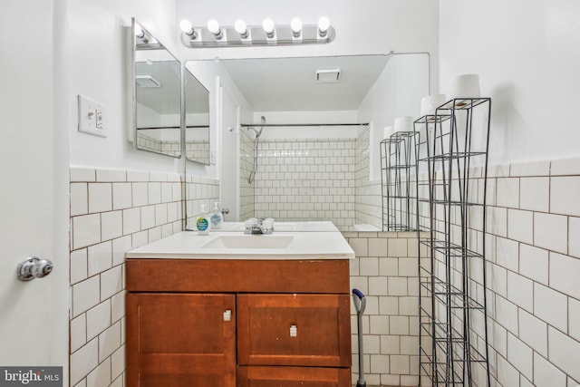 bathroom with tile walls, vanity, and a tile shower