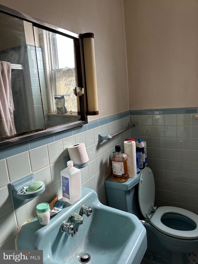 bathroom with toilet, sink, and tile walls