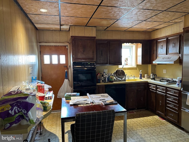 kitchen featuring wood walls, black appliances, ventilation hood, sink, and dark brown cabinetry