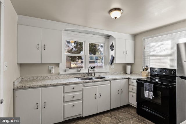 kitchen with white cabinets, light stone countertops, black range with electric cooktop, and sink