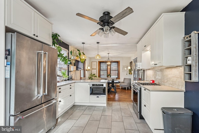 kitchen featuring white cabinetry, kitchen peninsula, ceiling fan with notable chandelier, high end appliances, and pendant lighting