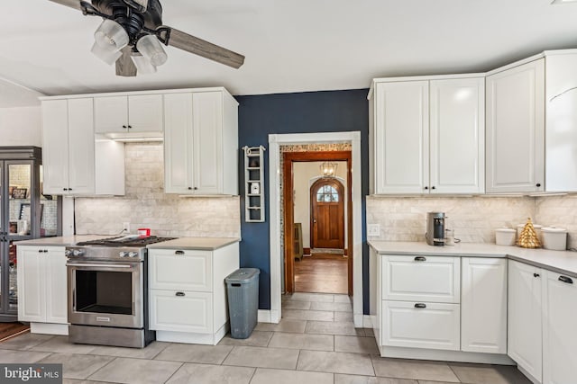 kitchen with ceiling fan, white cabinetry, light tile patterned floors, and high end stainless steel range oven