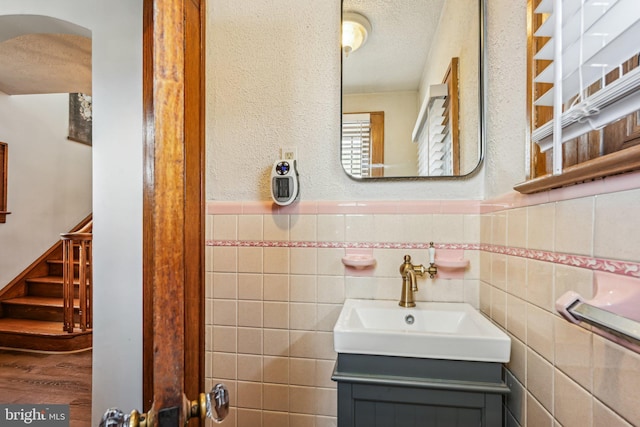 bathroom with tile walls, a textured ceiling, and vanity