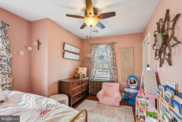 bedroom with ceiling fan, light hardwood / wood-style floors, and radiator