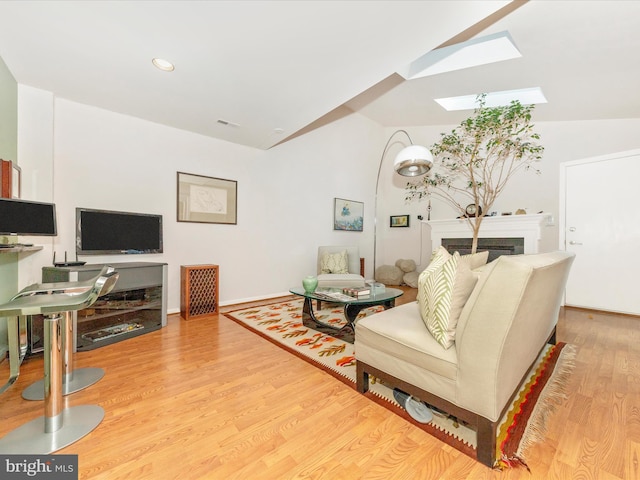 living room featuring light hardwood / wood-style floors and lofted ceiling with skylight