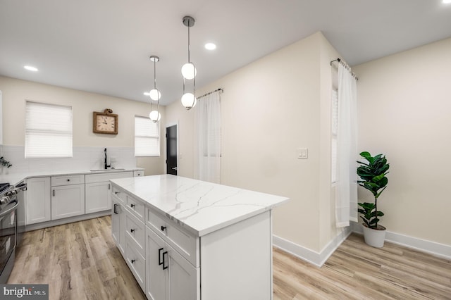 kitchen with light stone countertops, a center island, backsplash, decorative light fixtures, and white cabinets