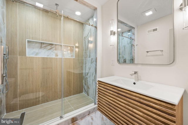 bathroom featuring a shower with door and vanity