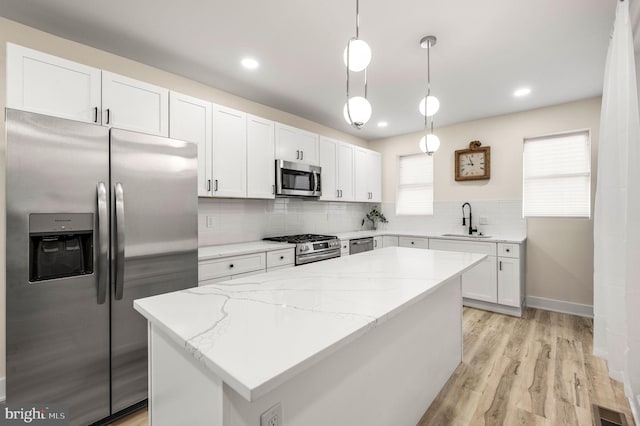 kitchen featuring pendant lighting, white cabinets, sink, appliances with stainless steel finishes, and a kitchen island