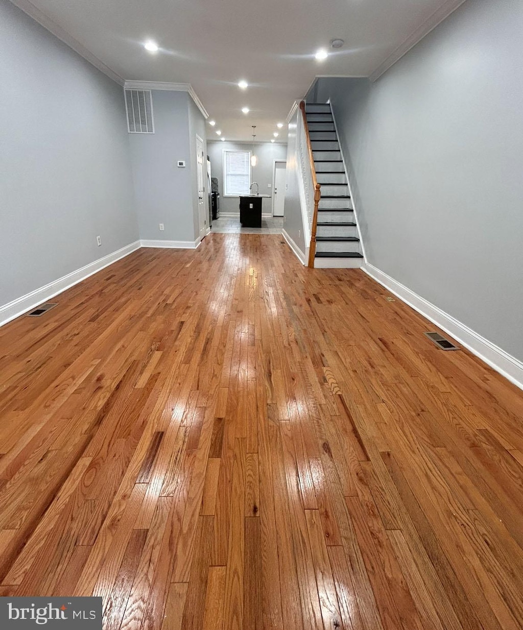 unfurnished living room with light wood-type flooring and crown molding