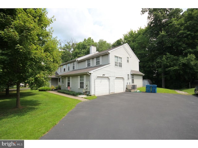 view of front of property with central AC, a garage, and a front lawn