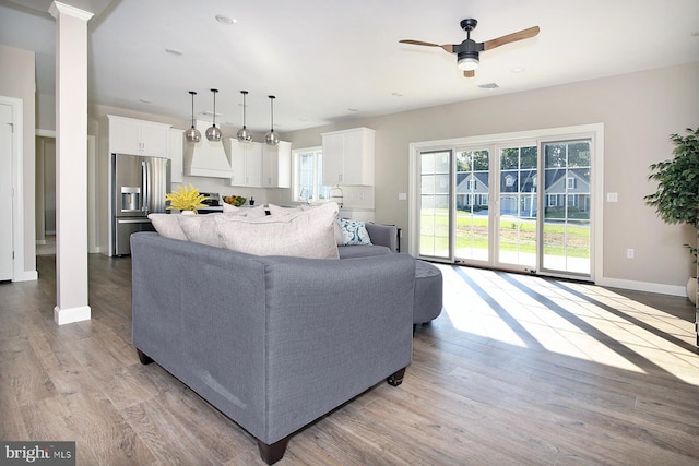 living room featuring light hardwood / wood-style floors, ceiling fan, and decorative columns