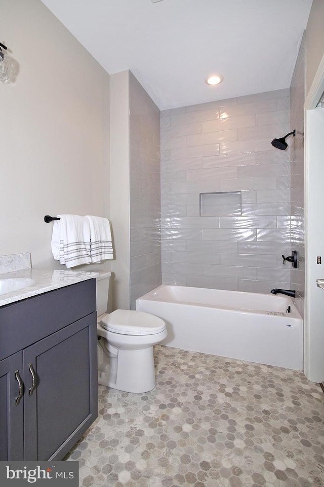 full bathroom with vanity, tiled shower / bath combo, and toilet