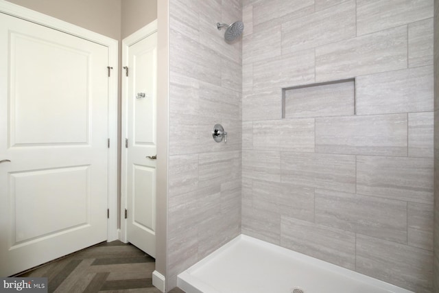 bathroom featuring a tile shower and parquet floors