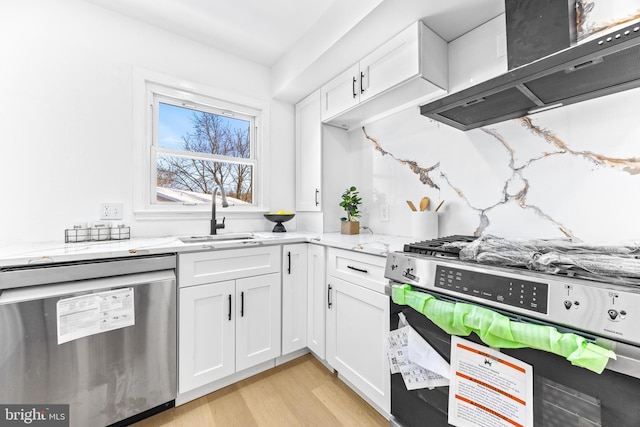 kitchen with white cabinetry, sink, stainless steel appliances, light stone counters, and exhaust hood