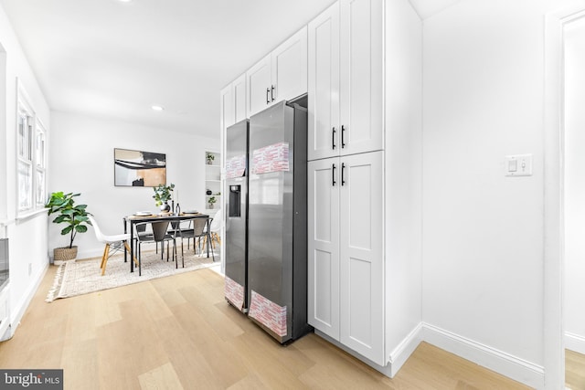 kitchen featuring stainless steel fridge with ice dispenser, light hardwood / wood-style flooring, and white cabinetry