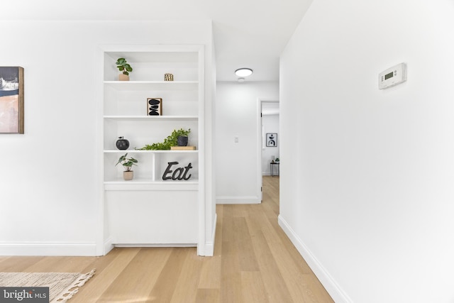 corridor with built in shelves and wood-type flooring