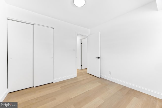 unfurnished bedroom with light wood-type flooring and a closet