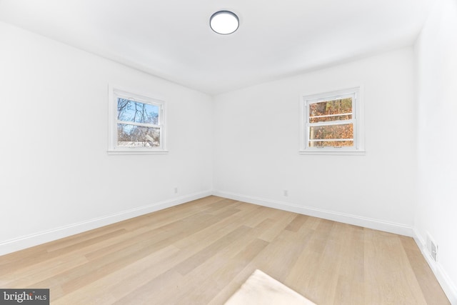 spare room featuring a wealth of natural light and light hardwood / wood-style floors