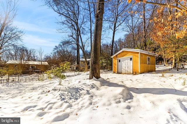 yard covered in snow with a garage and an outdoor structure