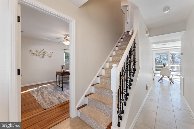 stairway with ceiling fan and tile patterned flooring