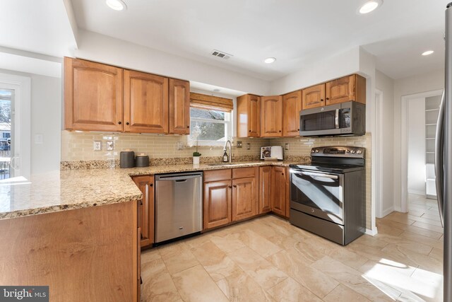 kitchen featuring sink, stainless steel appliances, light stone counters, and tasteful backsplash