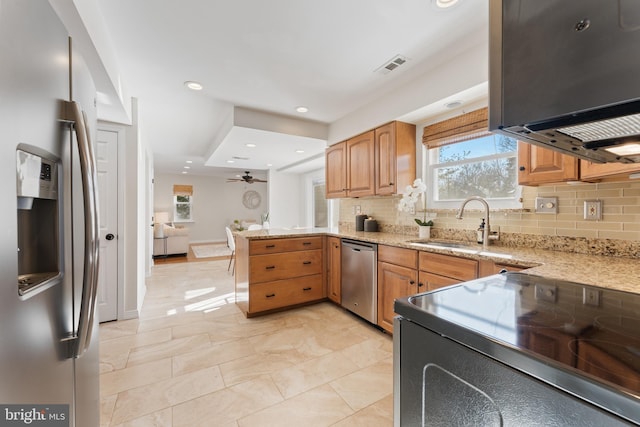 kitchen with kitchen peninsula, tasteful backsplash, appliances with stainless steel finishes, ceiling fan, and sink