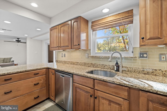 kitchen with stainless steel dishwasher, sink, ceiling fan, and light stone counters
