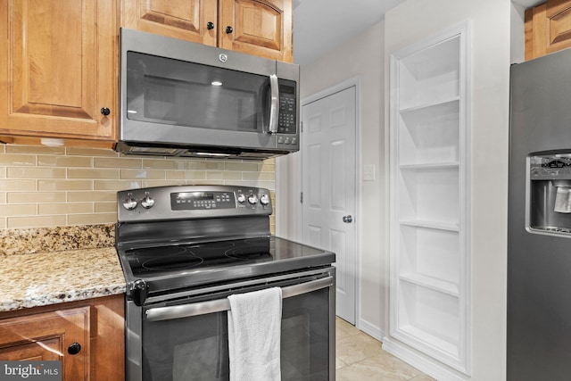 kitchen featuring stainless steel appliances, light tile patterned flooring, light stone counters, and tasteful backsplash