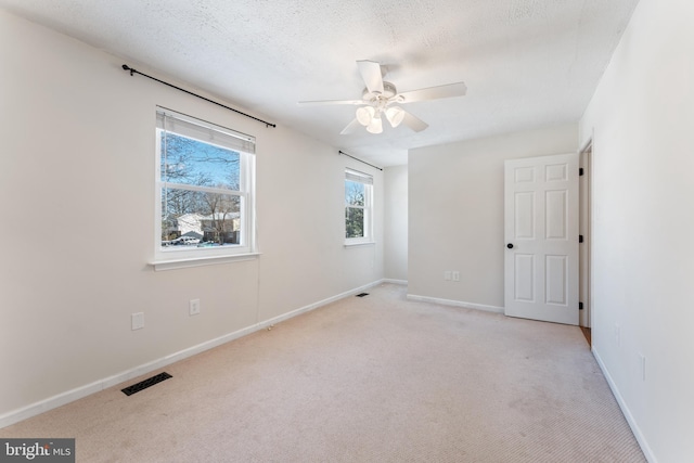 carpeted spare room with a textured ceiling and ceiling fan