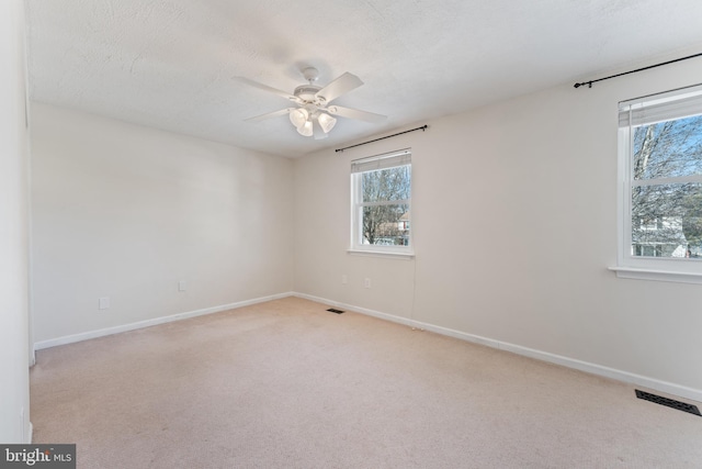 unfurnished room with a textured ceiling, ceiling fan, and light carpet