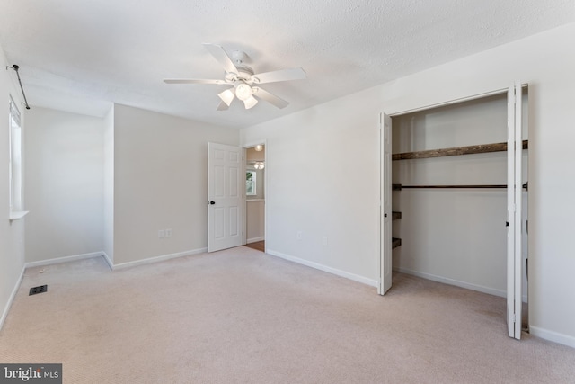 unfurnished bedroom featuring a closet, light carpet, ceiling fan, and a textured ceiling