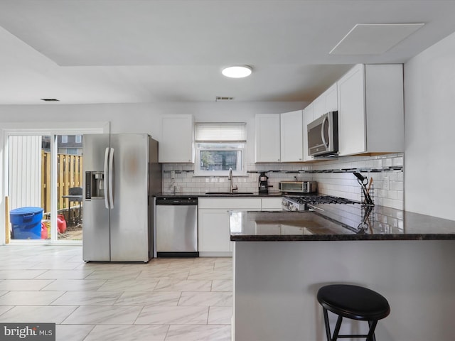 8387 Revelation Ave, Walkersville, MD 21793 - kitchen with white cabinets, stainless steel appliances, backsplash, a sink, and dark stone counters