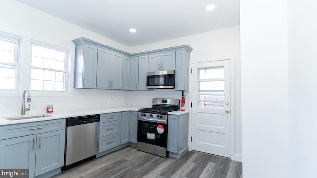 kitchen with gray cabinets, appliances with stainless steel finishes, dark wood-type flooring, sink, and backsplash