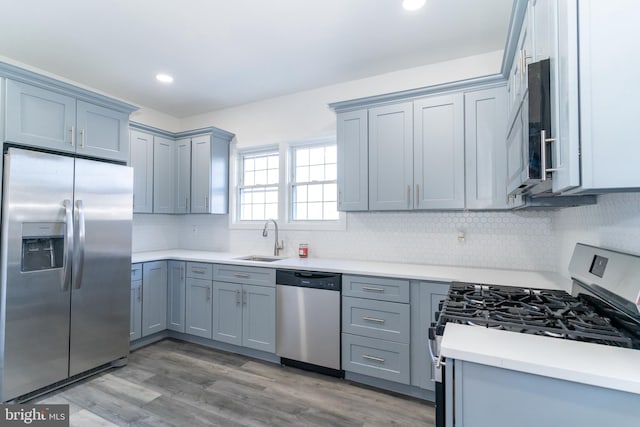 kitchen featuring hardwood / wood-style flooring, appliances with stainless steel finishes, decorative backsplash, and sink