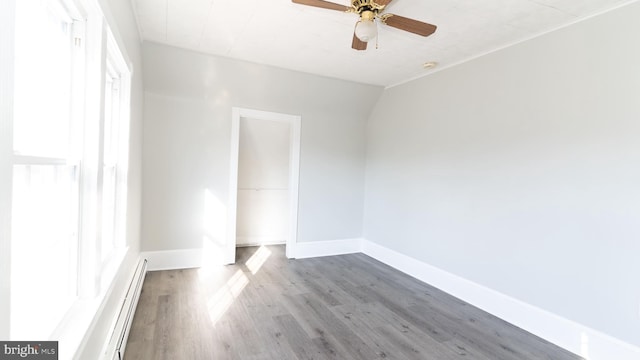 unfurnished room with a baseboard heating unit, hardwood / wood-style floors, and ceiling fan