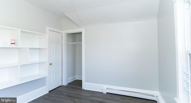 unfurnished bedroom with baseboard heating, dark wood-type flooring, and a closet